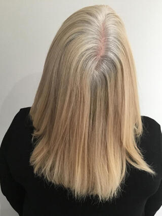 Before photo: rear view of woman with medium-length blonde hair with streaks of black before colour.
